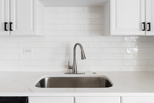 A kitchen with white cabinets, subway tile backsplash, and marble countertop.