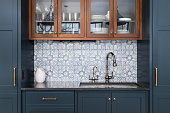 A kitchen with blue cabinets and mosaic tile backsplash.