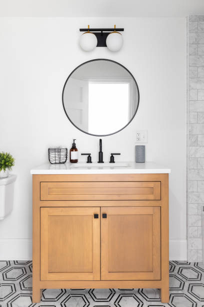 A bathroom with a tiled floor and wood cabinet. A beautiful bathroom with a wood vanity, custom tile shower and floor, and a sliding glass door with black hardware. vanity stock pictures, royalty-free photos & images