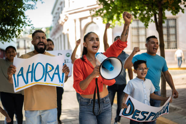 istock Mid adult protester woman leading a demonstration using a megaphone 1436219175