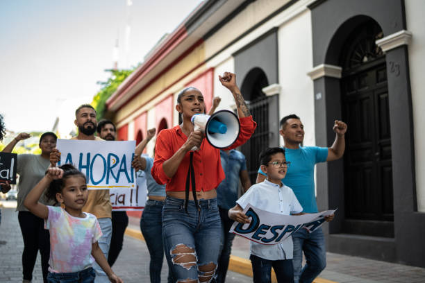 istock Mid adult protester woman leading a demonstration using a megaphone 1436220692