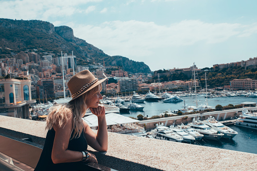 Young female traveler enjoying great view on the harbor with yachts in Monte Carlo in Monaco. Famous tourist destination on Mediterranean sea,  Cote d'Azur, France, South Europe. Copy space