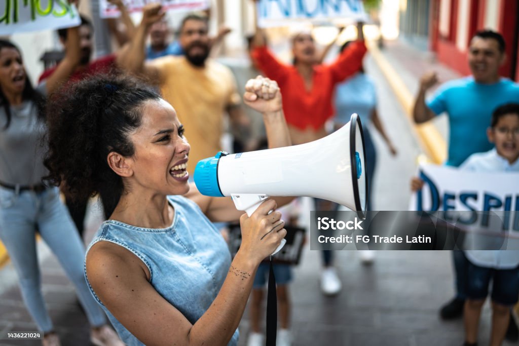Mid adult woman leading a demonstration using a megaphone outdoors 30-34 Years Stock Photo