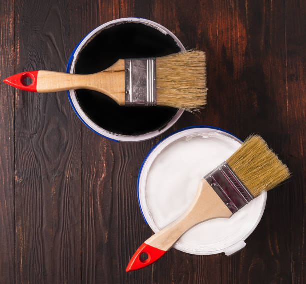istock Open can with white and black paint and brushes on wooden background, top view 1436224428