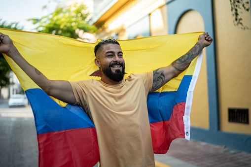 Mid adult man holding Ecuadorian flag in the street