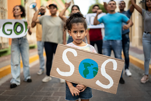 Portrait of child girl holding a sign about the environment on the protest