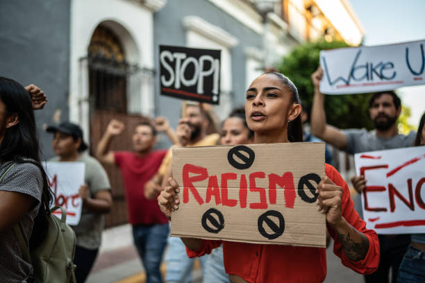 Mid adult woman walking while holding a sign about the racism on a protest