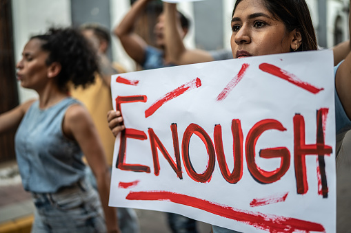 Mid adult woman walking while holding a sign on a protest