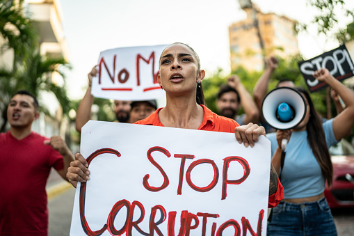 Mid adult woman holding signs against corruption on a protest