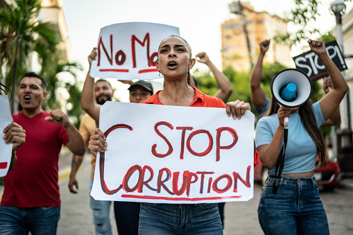 Mid adult woman holding signs against corruption on a protest