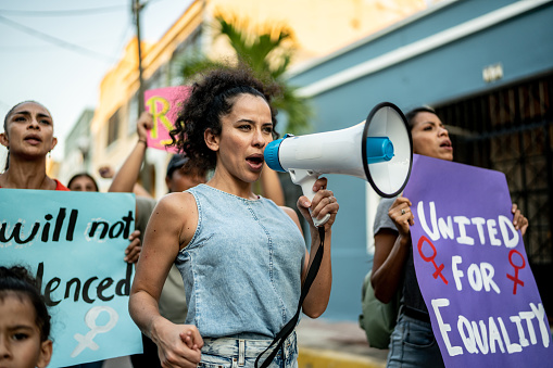 Mid adult woman leading a demonstration using a megaphone outdoors