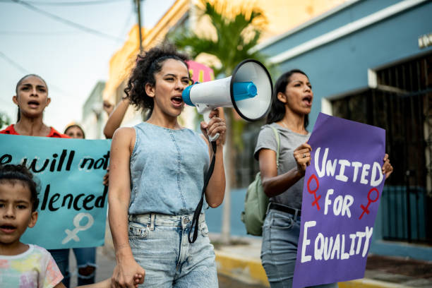 Mid adult woman leading a demonstration using a megaphone outdoors Mid adult woman leading a demonstration using a megaphone outdoors gender equality stock pictures, royalty-free photos & images