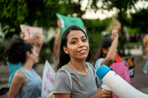 Portrait of young woman with a megaphone on a protest outdoors-