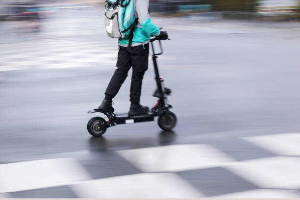 istock person with an electric scooter on the road 1436228128