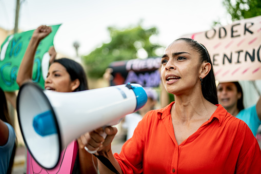 Mid adult woman leading a demonstration using a megaphone outdoors