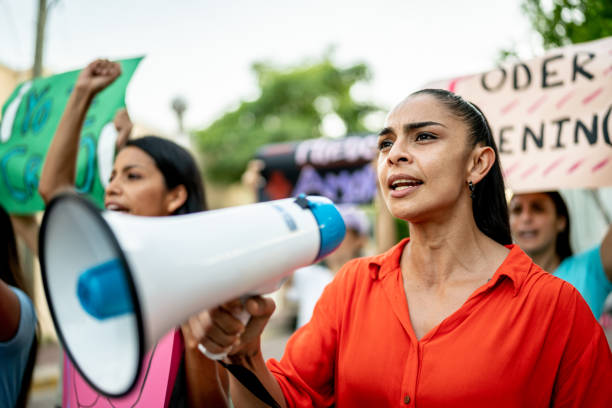 Mid adult woman leading a demonstration using a megaphone outdoors Mid adult woman leading a demonstration using a megaphone outdoors announce stock pictures, royalty-free photos & images