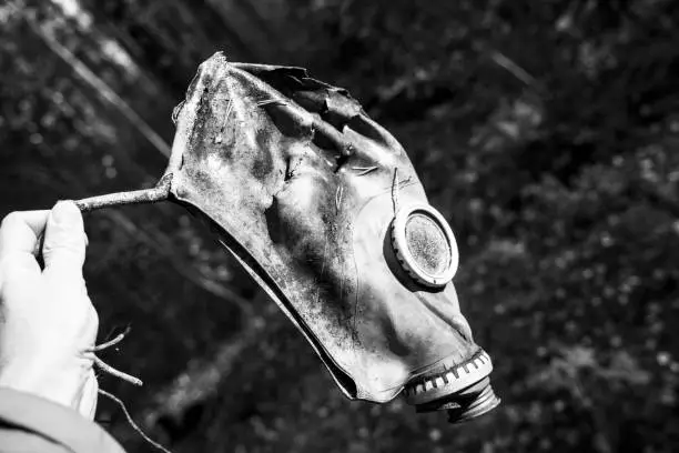 Photo of an old used gas mask in the hand of a man in the forest