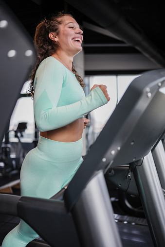 Beautiful young cheerful women in sportswear running on a treadmill at the gym. Sporty beauty.