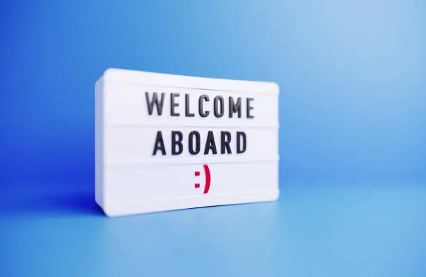 Welcome aboard written white lightbox sitting on blue background. Horizontal composition with copy space.