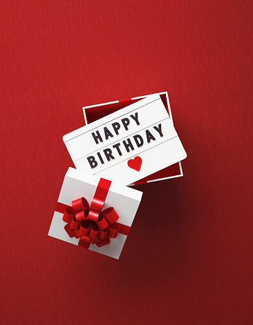 Happy Birthday written lightbox sitting over white gift box on red background. Vertical composition with copy space, Great use for birthday concepts.