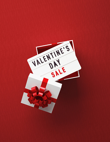 Valentine's Day Sale written lightbox sitting over white gift box on red background. Vertical composition with copy space, Great use for Valentine's Day Sale concepts.