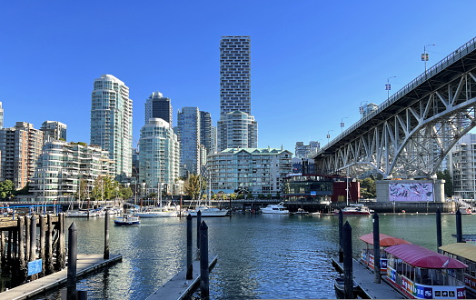 Bridge to greenville and water bus passing under the bridge Nature Canada Vancouver Pacific Ocean Pier and pillars on the pier Granville Island aquabus Skyscrapers in the background 09.2022 Canada