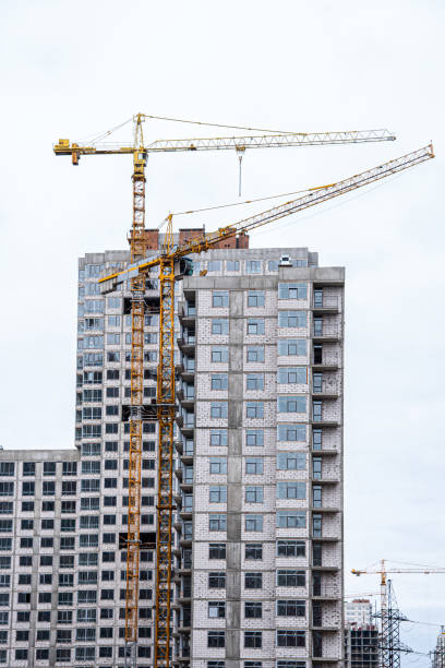 istock Crane and building under construction against white sky 1436257854