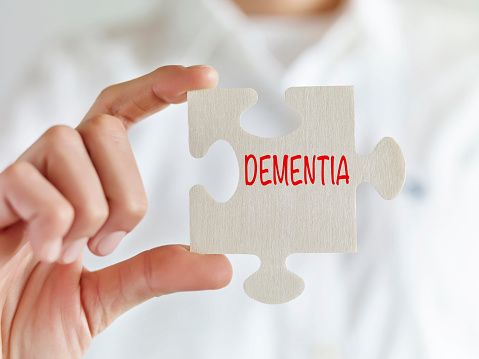 Woman holding jigsaw puzzle pieces with “Dementia” text