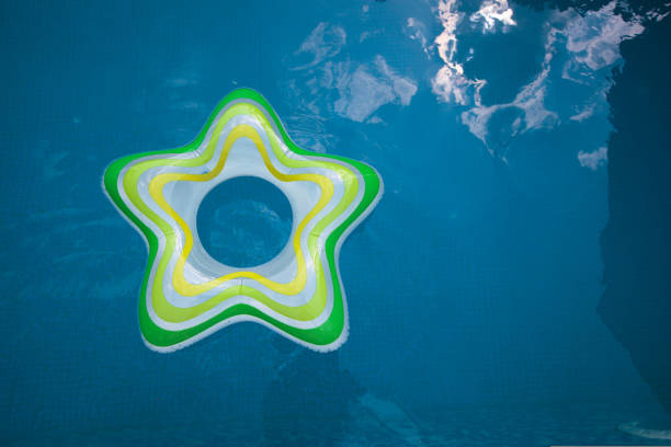 Smiling girl floating on a green inflatable ring in a bright blue pool