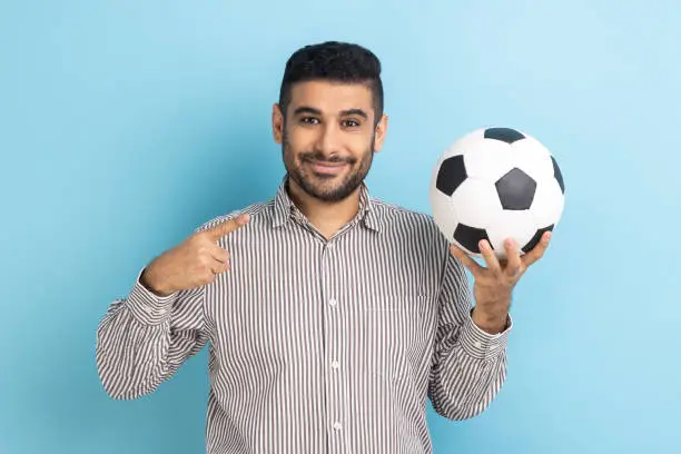 Photo of Handsome businessman pointing finger at soccer ball on his hand with smiling positive expression.