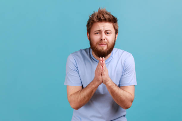 istock Man holding arms in prayer, asking help or forgiveness with imploring eyes sincere asking permission 1436259554
