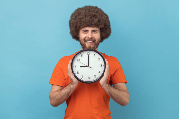 istock Man holding in hands big wall clock looking at camera with happy expression. 1436260203