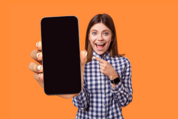 istock Amazed woman pointing at smart phone with empty display, copy space for advertisement. 1436260527