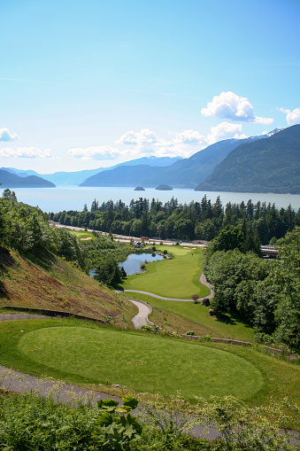 A view overlooking a golf fairway from the starting tees, with the Howe Sound and mountains in the background. Located near Squamish, British Columbia, Canada.