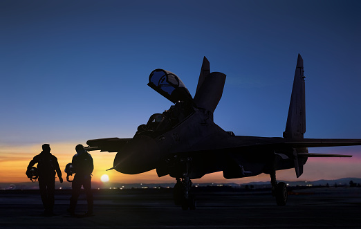 Jet fighter pilot walking during sunset at air force base airfield