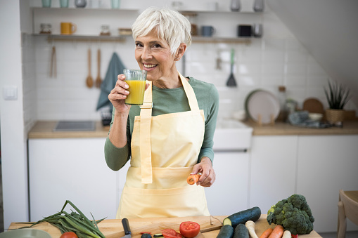 Portrait of woman while holding juice in her kitchen