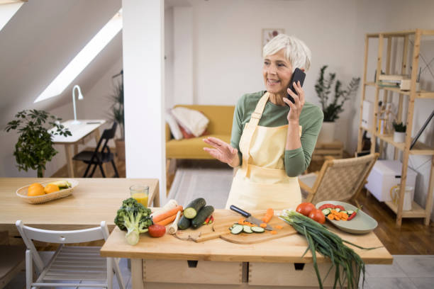 istock Woman talking on mobile in kitchen 1436277283