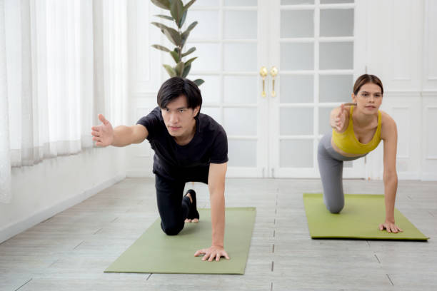 istock Young woman and man practicing workout with posing plank while stretching hands and leg on mat at home, female and male doing weight training with strength and strong, two people, sport concept. 1436283871