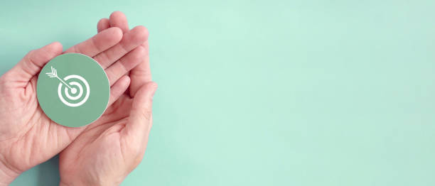 Hand holding target paper cut, achieve on point, sustainable challenge goal, business objective plan concept