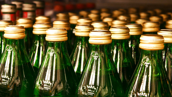 Many green glass bottles of mineral water with metallic caps close-up