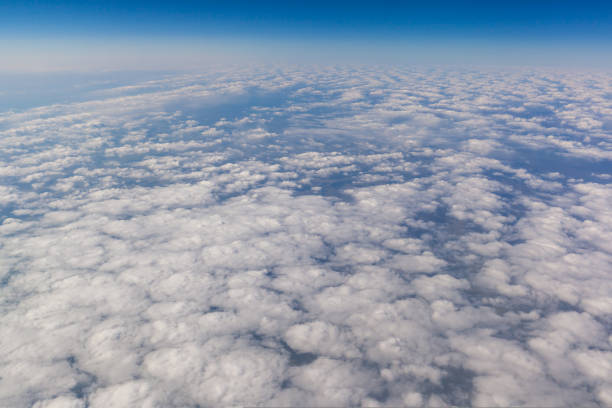Airplane flight. Wing of an airplane flying above the clouds. View from the window of the plane. Airplane, Aircraft. Traveling by air. Aircraft's wing and land seen through the illuminator.