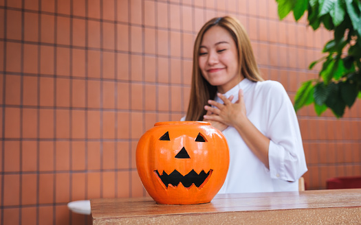 Portrait image of a beautiful young woman looking at a Halloween pumpkin bowl for Halloween festival concept