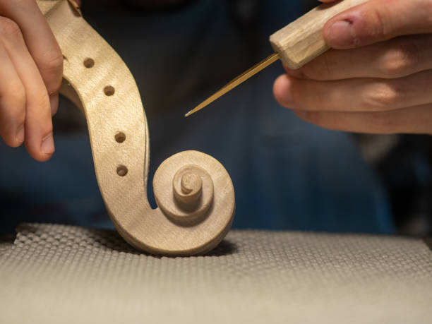 istock luthier artisan maker sculpting and carving violin scroll and neck with chisel 1436305893