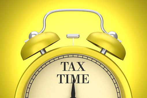 The yellow clock on the yellow background writes Tax. Planning concept.