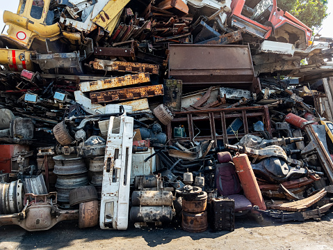Old rusty and damaged car parts in junkyard