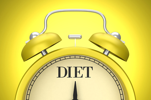 The yellow clock on the yellow background writes Diet. Planning concept.