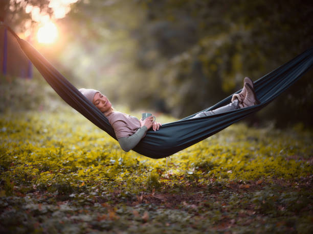 Young smiling woman relaxing in hammock with her eyes closed during autumn day at sunset. Copy space. Photographed in medium format.