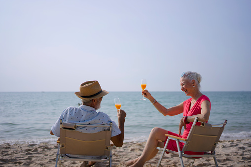 Senior couple sitting and talking at the beach. Travel and leisure activity.