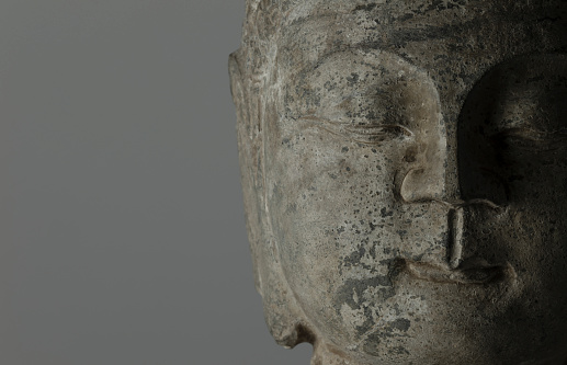 closeup of stone buddha head on white background