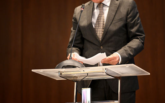 Midsection of business person at the lectern, delivering speech